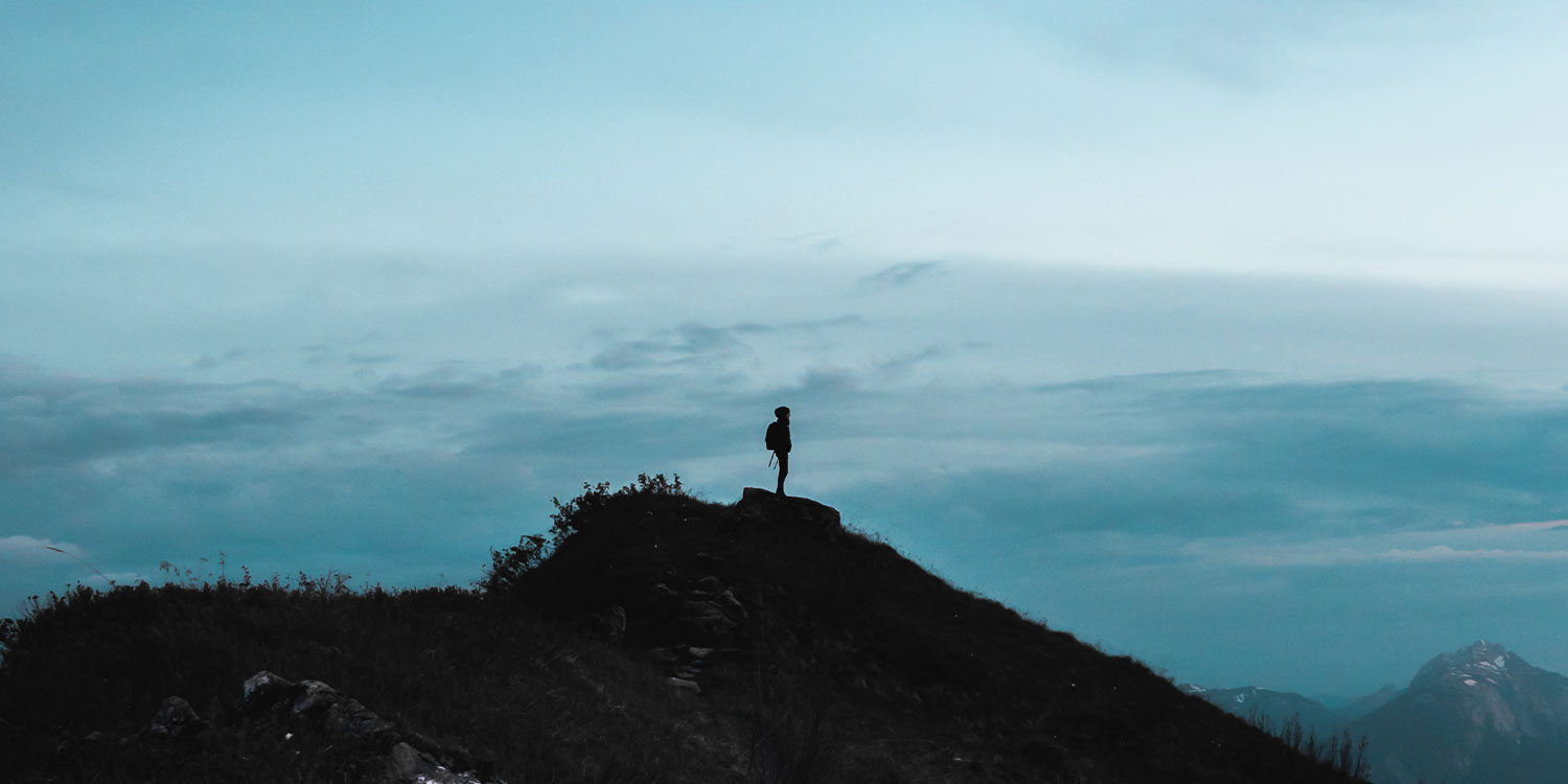 Photo d'une personne dans la pénombre au sommet d'une montagne