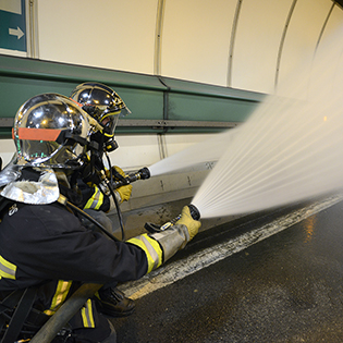 Exercice du Tunnel du Mont Blanc : pompiers en train d'éteindre le feu avec des lances d'incendie